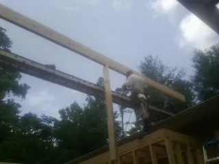 Carpenter setting a ridge beam over a new addition frame — Ice Dam Removal by Roofing Brothers in Mayo