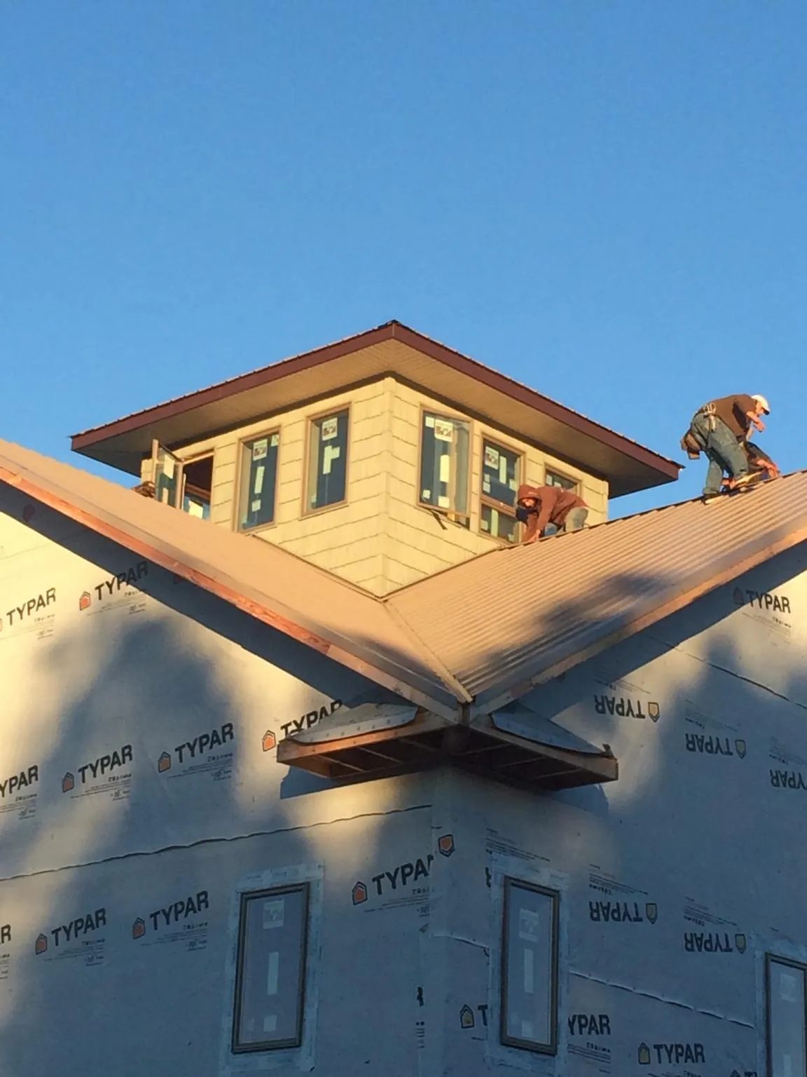 Roofers working around a rooftop cupola on a new metal roof at sunset — Roof Waterproofing in Mayo by Roofing Brothers